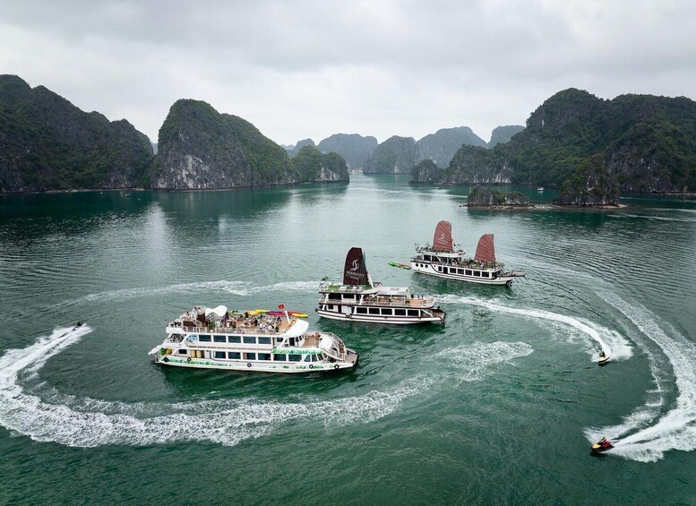 A group of boats on a calm river surrounded by lush green mountains. 1