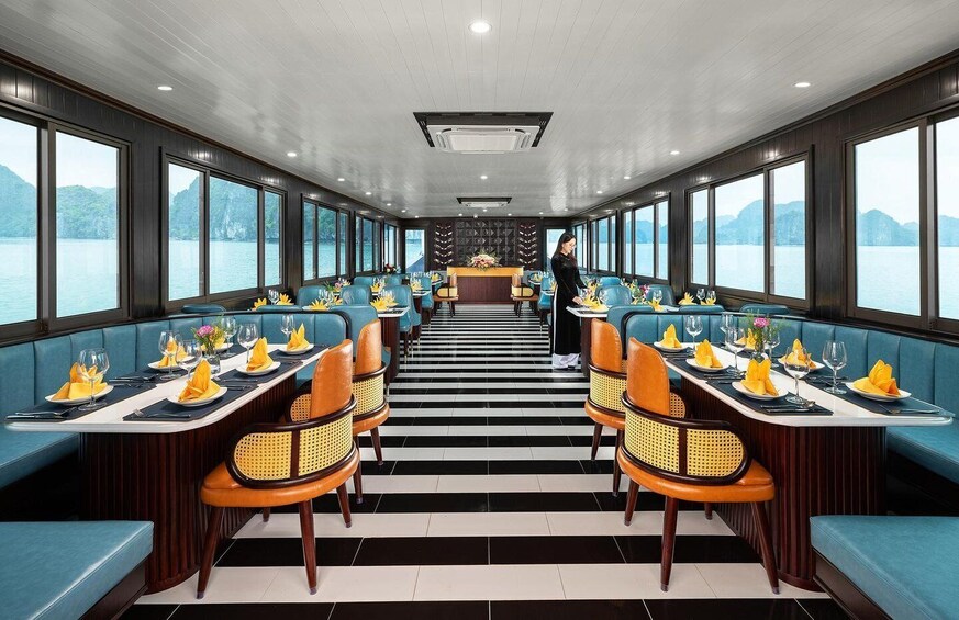 A restaurant with blue booths and tables, a black and white striped floor, and large windows overlooking the water. 5