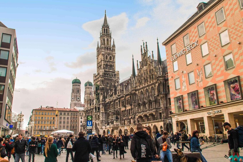 A busy urban square with historic buildings, including a prominent cathedral with a tall spire. 2