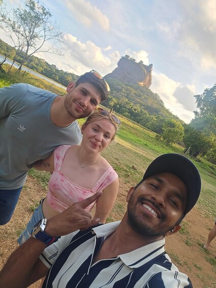 Three people outdoors with a mountainous landscape in the background. 2