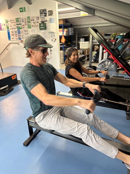 Two people using rowing machines in a gym. 3