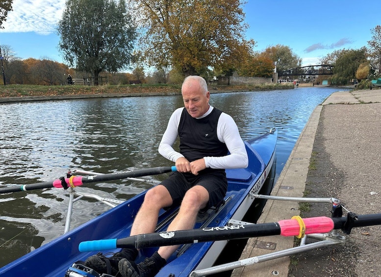 A man rowing a blue boat on a calm river. 2