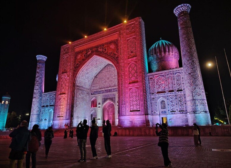 A large, illuminated building with intricate patterns and domes, surrounded by people. 2