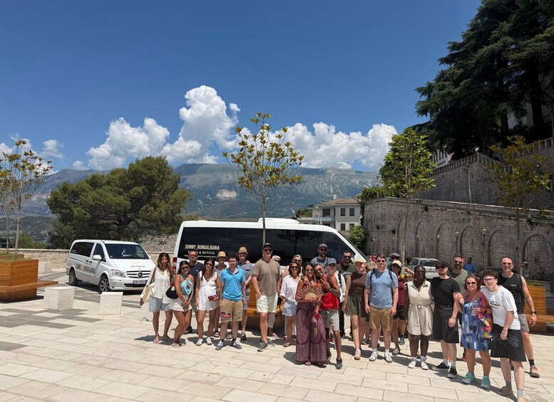 A group of people posing in front of a white van with 'Sunny Rungabalnia' on the side, set against a backdrop of mountains and clear blue sky. 2