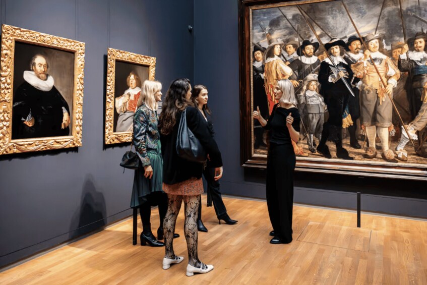 An art gallery with visitors observing paintings. 5