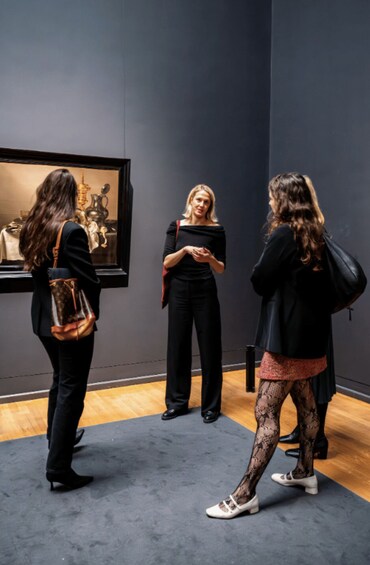 Three people in an art gallery, conversing in front of a painting. 2