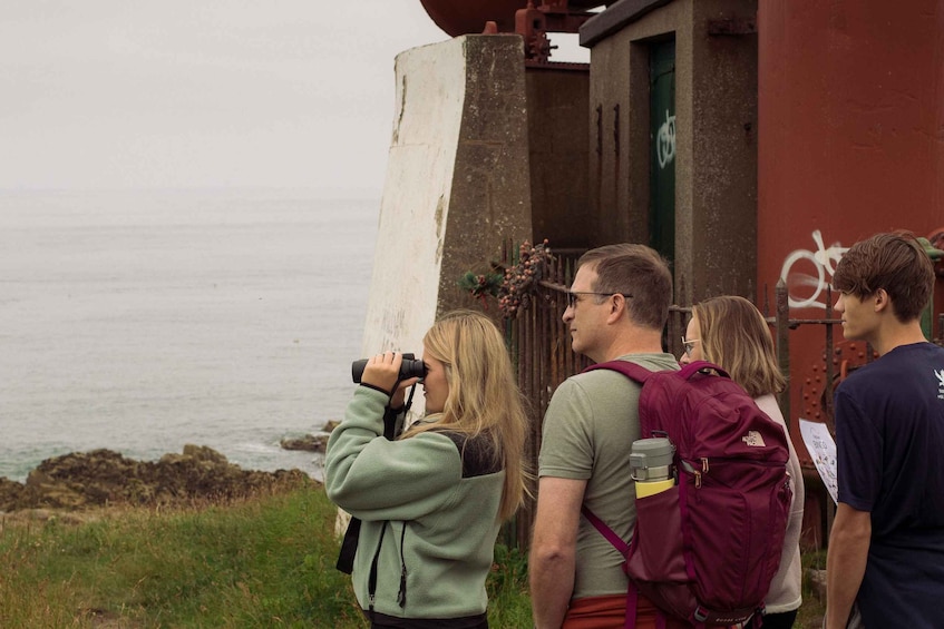 A group of people standing by a coastal structure, looking out at the sea. 2