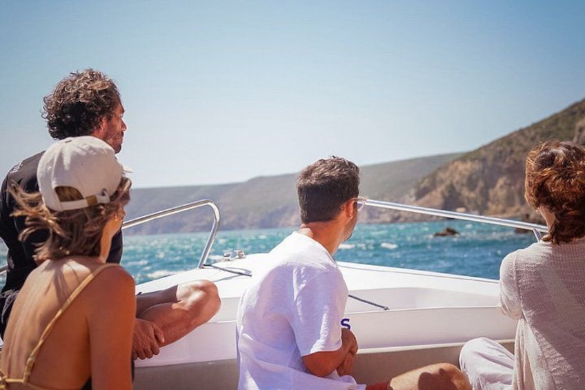 A group of people on a boat with a clear view of the sea and distant hills. 2