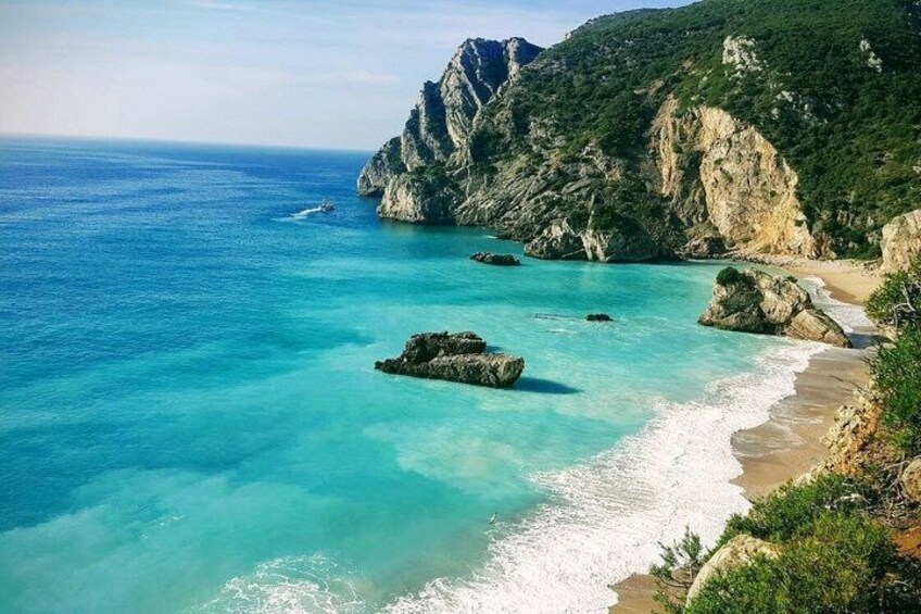 A coastal landscape with clear turquoise waters, rocky outcrops, and a sandy beach. 2