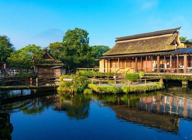 A traditional Japanese building by a calm waterway with a wooden bridge and lush greenery. 3