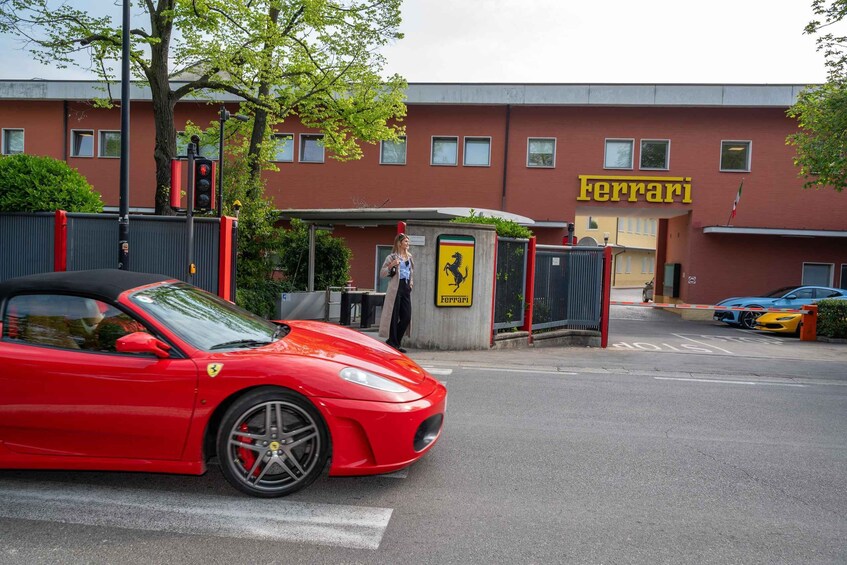 A red Ferrari convertible parked in front of a building with a Ferrari logo. 4
