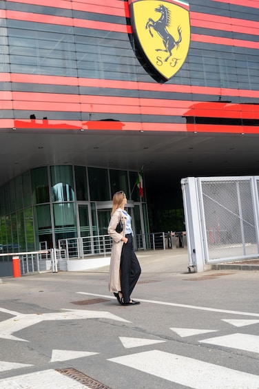 A person walking in front of a building with a Ferrari logo. 2