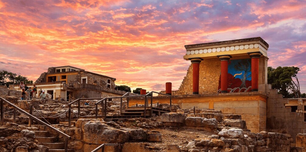 Ancient ruins with columns and a mural, set against a sunset sky. 2