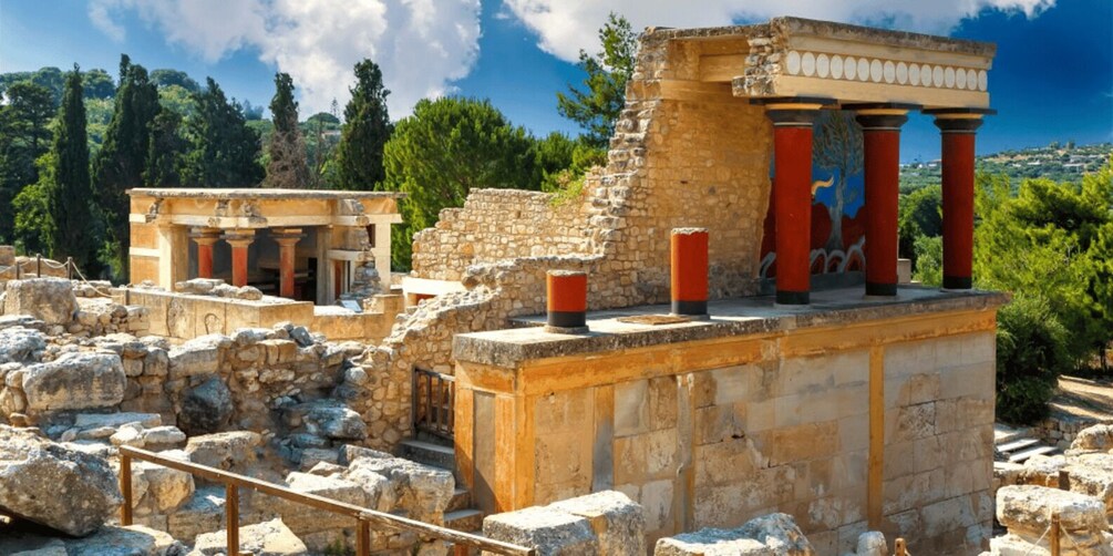 Ancient ruins with columns and stone structures, set against a backdrop of trees and a clear sky. 3