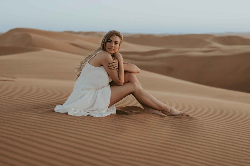 A person sitting on a sand dune in a desert landscape. 1