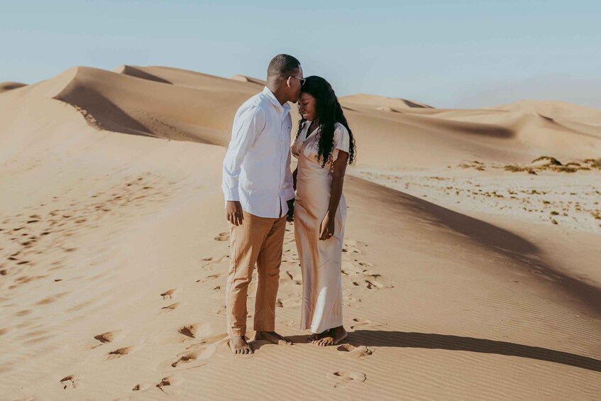A couple standing on a sand dune in a desert landscape. 4