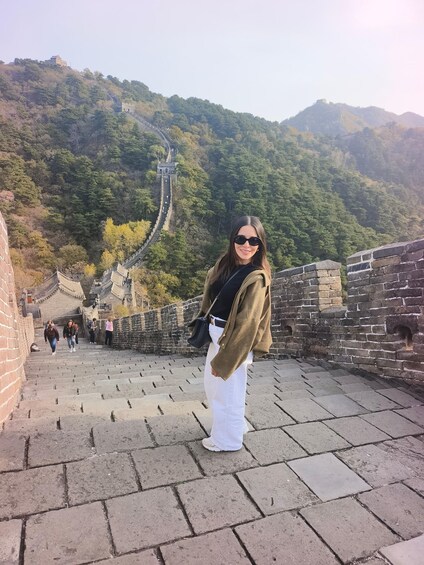 A person standing on the Great Wall of China with a mountainous landscape in the background. 3