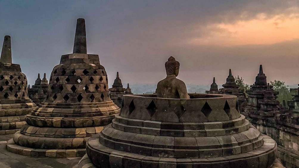 A collection of ancient stone stupas with a central seated Buddha statue. 4