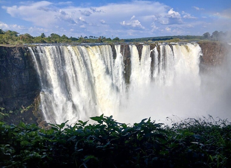 A large waterfall cascading down a rocky cliff surrounded by lush greenery. 3