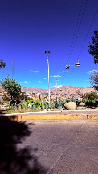 A clear blue sky, a road with a yellow curb, street lamps, and a distant mountain range. 5