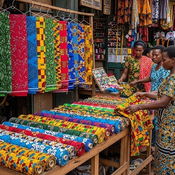 Colorful fabrics displayed on a table and hanging on a rack in a market. 1