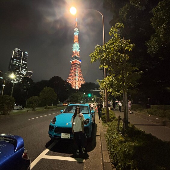 A blue car parked on the side of a road with the Eiffel Tower illuminated in the background. 3