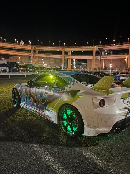 A sports car with a colorful design parked in a lot at night. 1