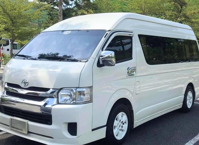 A white Toyota van parked on a street with trees in the background. 3