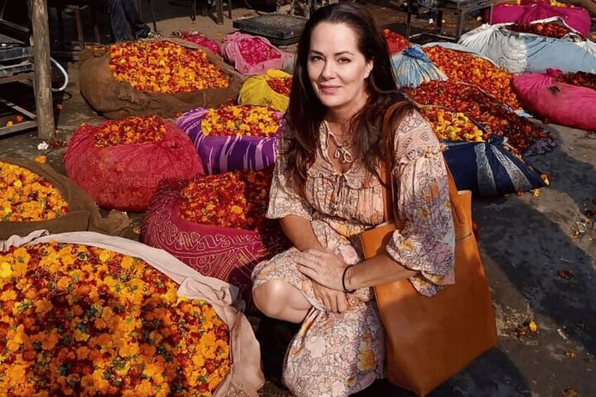 Una persona sentada entre coloridas bolsas llenas de flores. 3