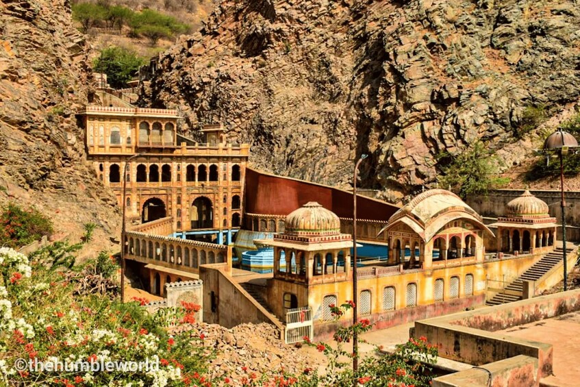 Un edificio histórico con ventanas arqueadas y estructuras abovedadas, situado frente a una ladera rocosa. 4