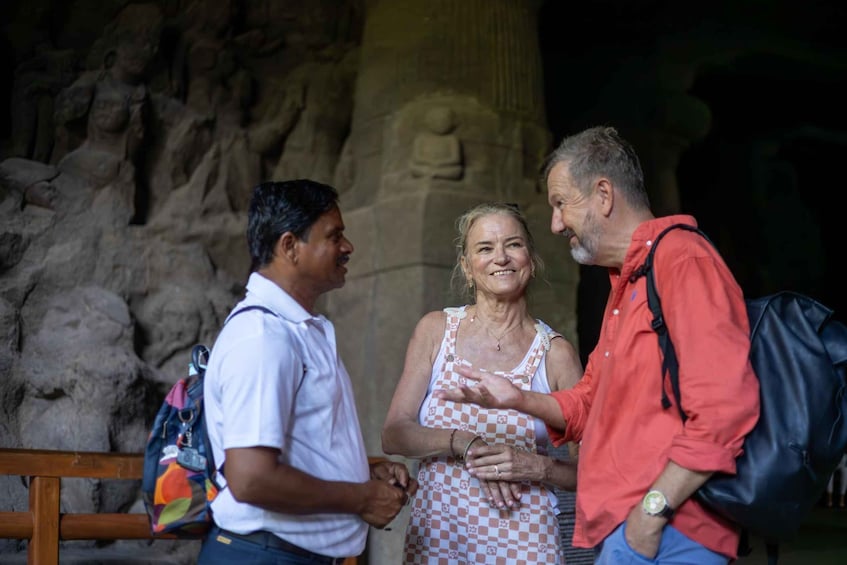 Tre persone che conversano di fronte a una grotta con una statua di Buddha. 3