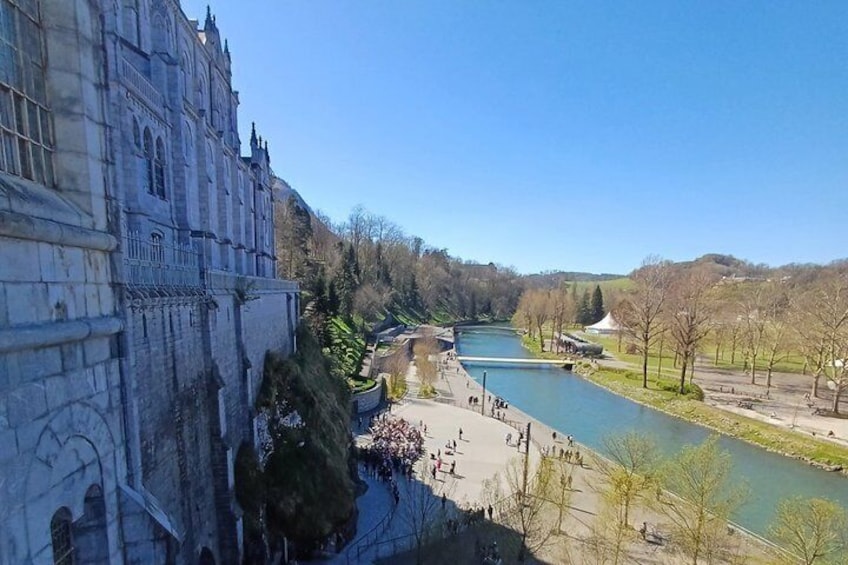 A river with a bridge, a large building, and a park with trees and people. 4