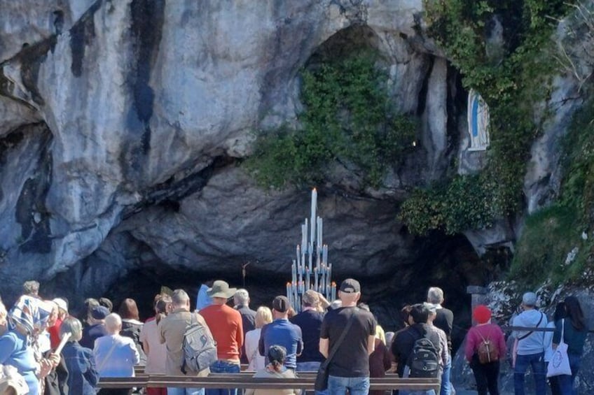 A crowd of people standing in front of a cave with a vertical structure inside. 2