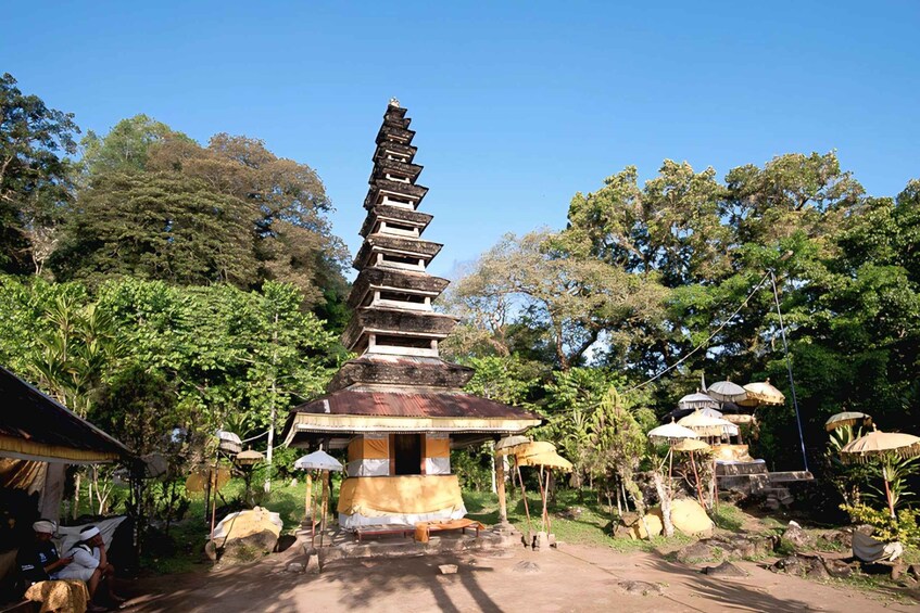 A traditional multi-tiered stupa surrounded by lush greenery and thatched umbrellas. 4