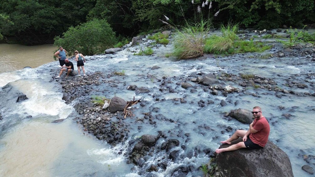 A river with rocks and people sitting on rocks. 2