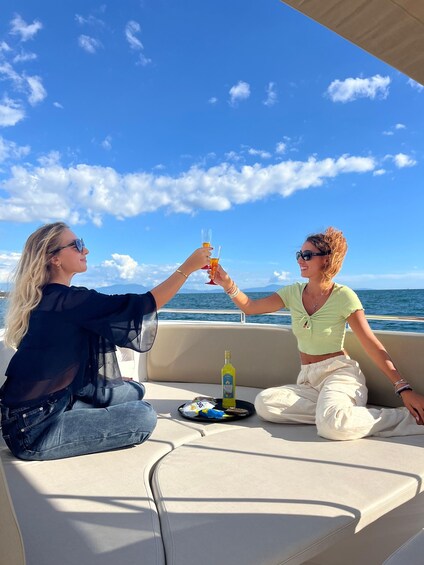 Two people toasting with drinks on a boat with a clear sky and ocean in the background. 1