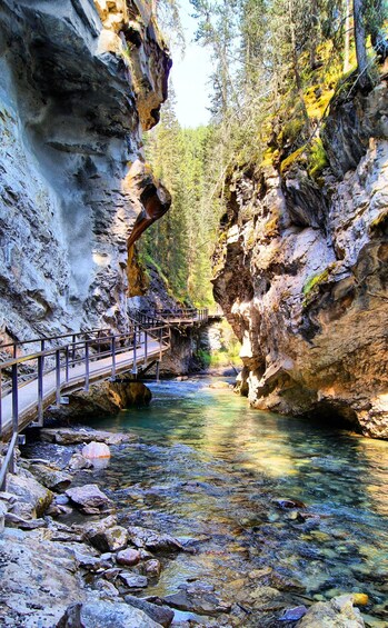 A river flowing through a rocky gorge with a bridge and a wooden walkway. 5
