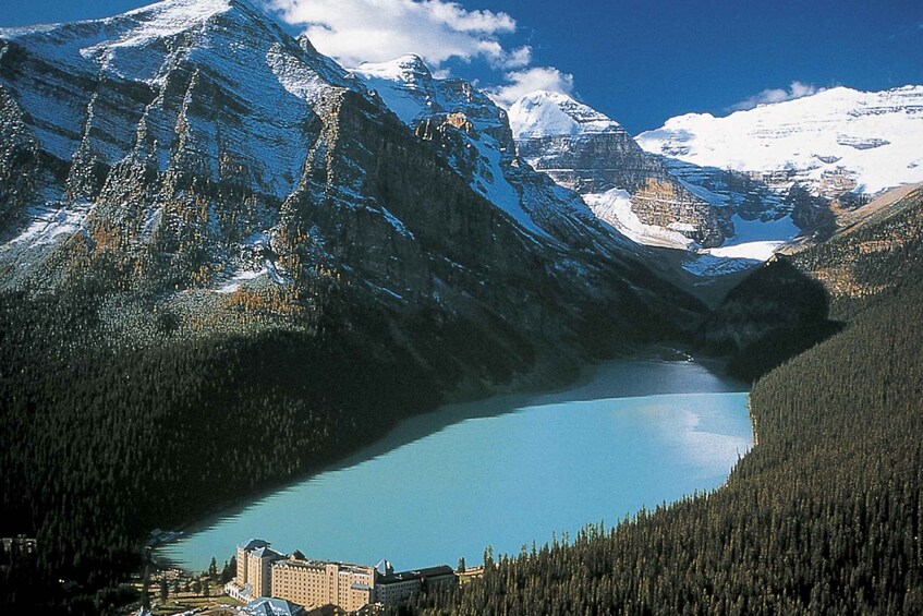 A mountain lake with snow-capped peaks, dense forests, and a lodge. 2