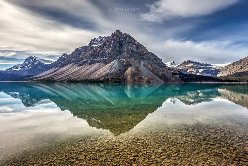 A mountain reflected in a clear lake with rocky shore. 4