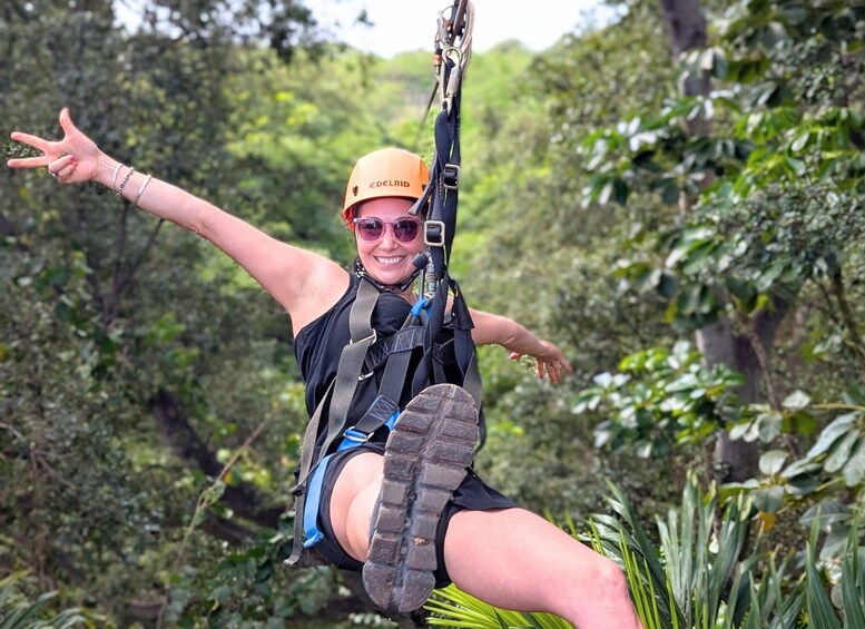 A person suspended in mid-air, wearing a harness and helmet, with a forested background. 4