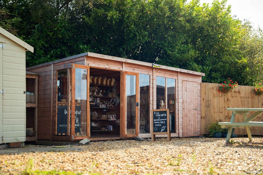 A wooden ice cream shop with a sign advertising ice cream and refreshments. 4