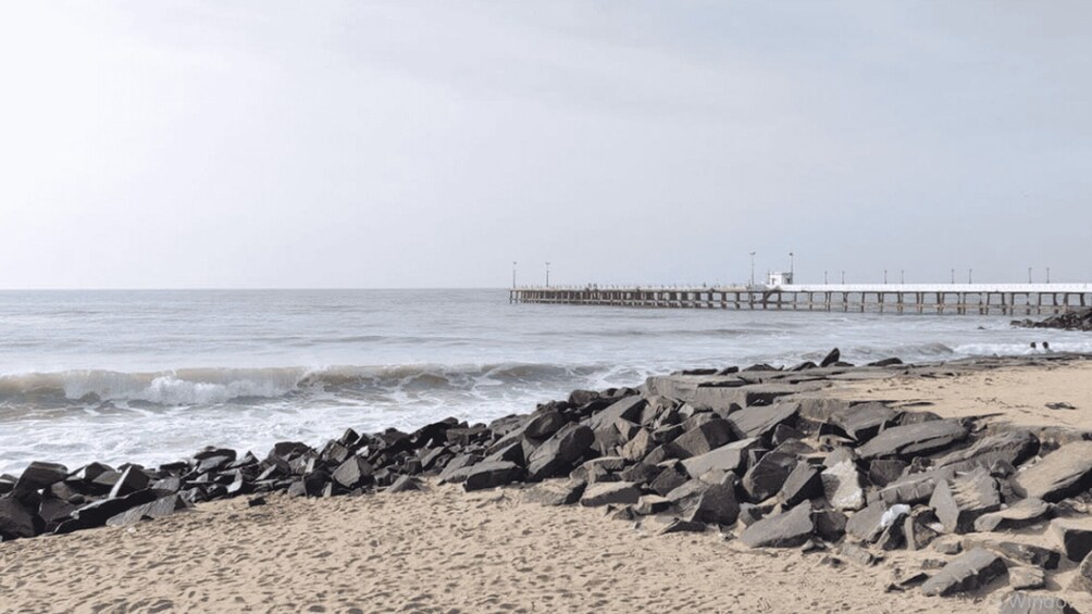 A beach with a rocky shoreline and a pier extending into the ocean. 2