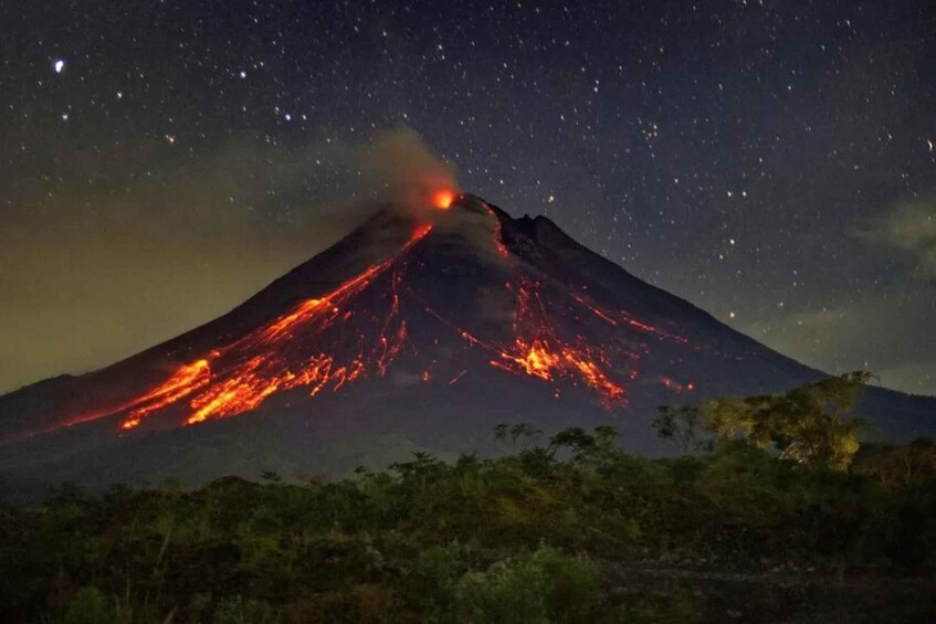 A volcano erupting at night with stars visible in the sky. 1