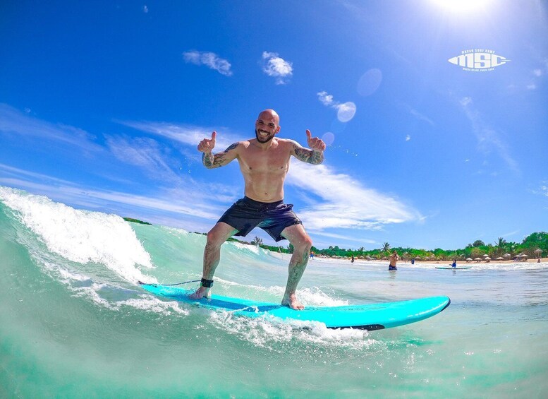 A man surfing on a wave with a clear blue sky and a beach in the background. 2