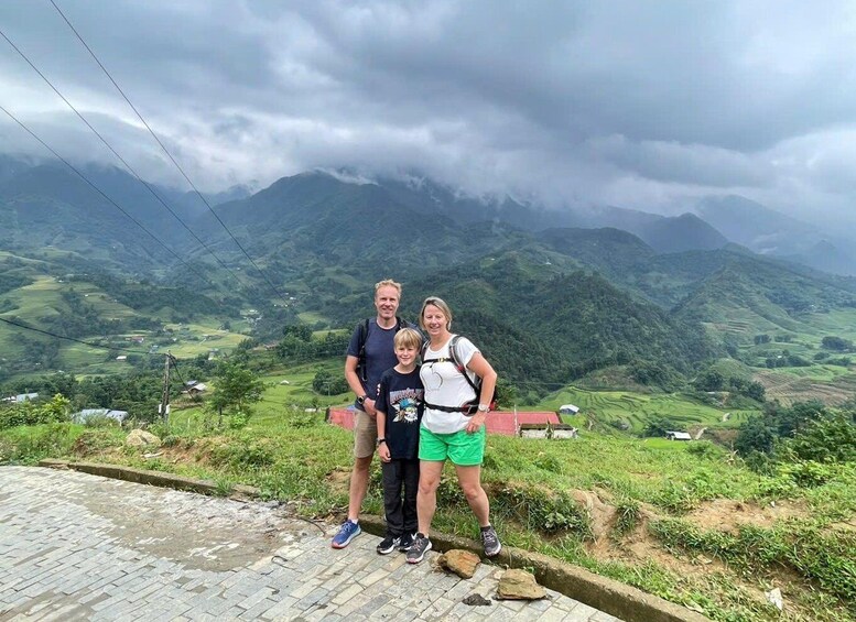 A family standing on a paved path with a mountainous landscape in the background. 4