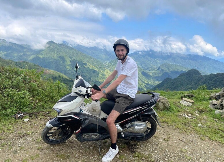 A person sitting on a motorcycle with a mountainous landscape in the background. 5