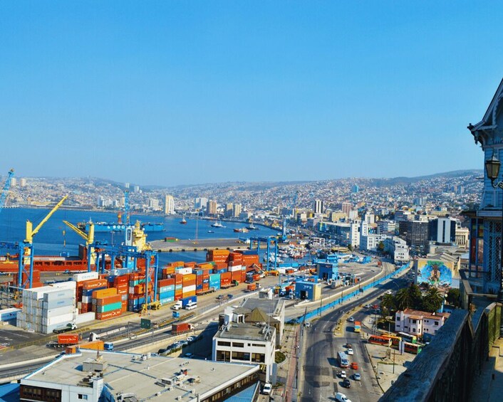 A port with shipping containers, cranes, and a cityscape in the background. 1