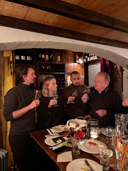 A group of people toasting with wine glasses at a wooden table in a rustic setting. 5