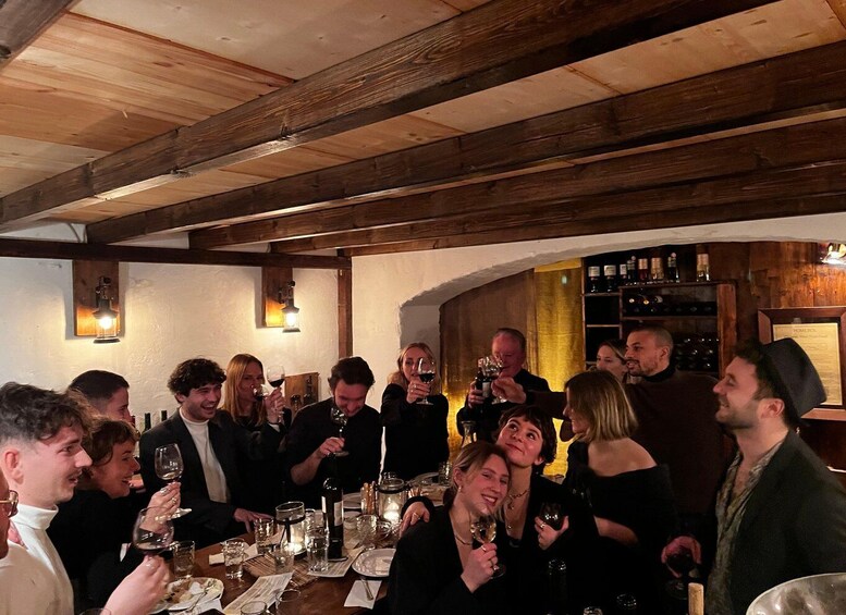 A group of people at a wine tasting event in a rustic cellar with wooden beams and dim lighting. 4