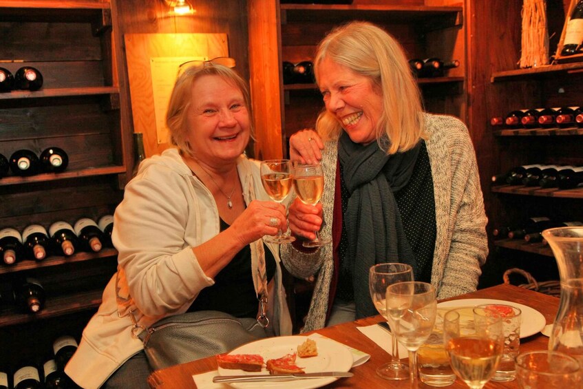 Two people toasting with wine glasses in a wine cellar. 2